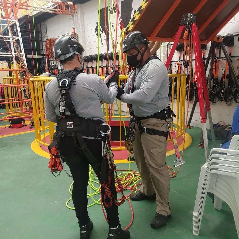 Equipe da AGCS em ação durante treinamento de trabalho em altura (NR 35), com uso de capacetes, cintos de segurança e equipamentos de ancoragem em centro de tre
